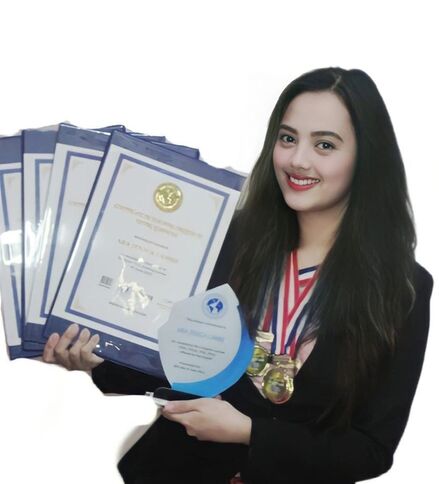 Photo of Ara Cambe with their Hai English certificates, medals, and plaque